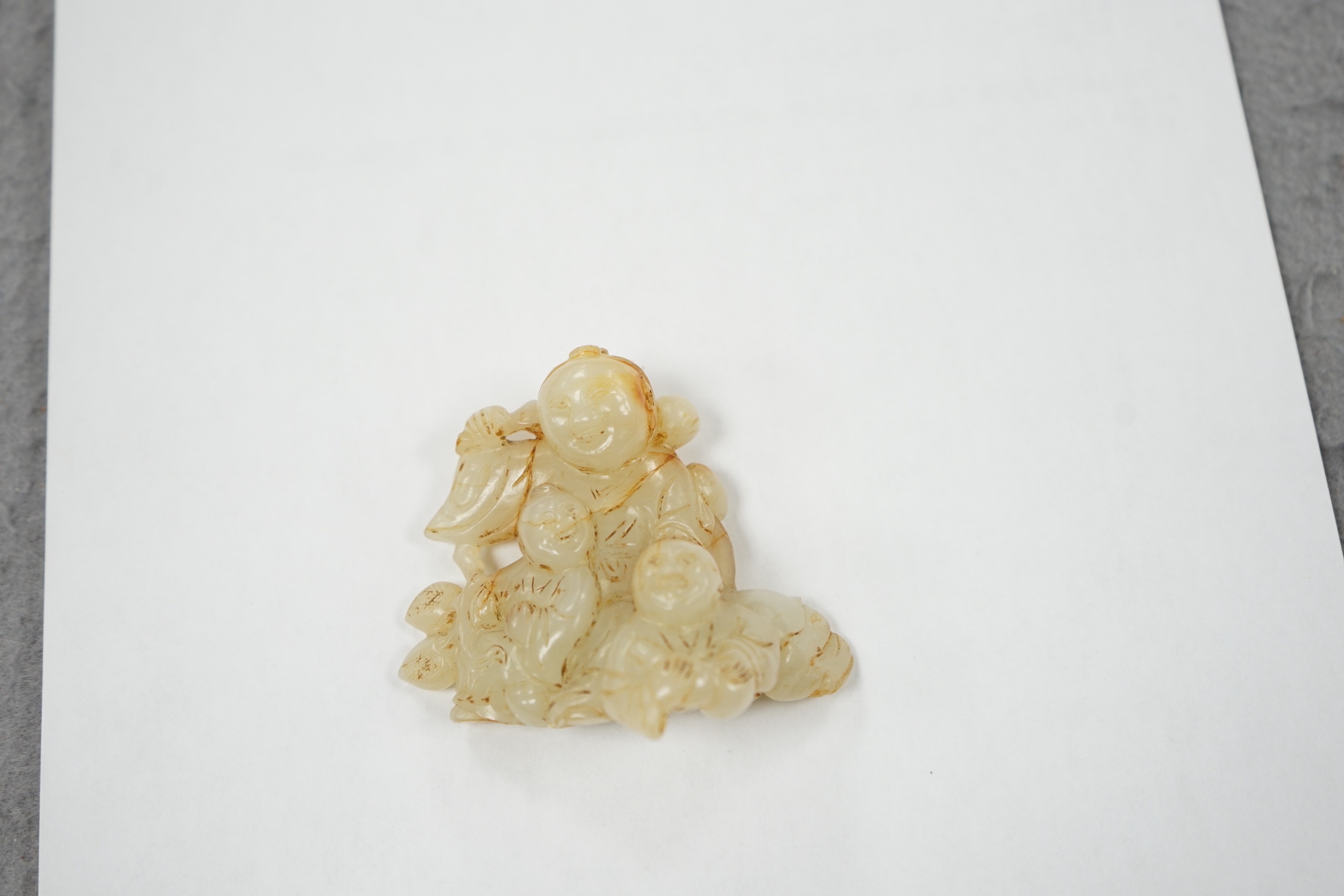 A Chinese white and russet jade group of three boys, 18th/19th century, 7.2 cm, wood stand